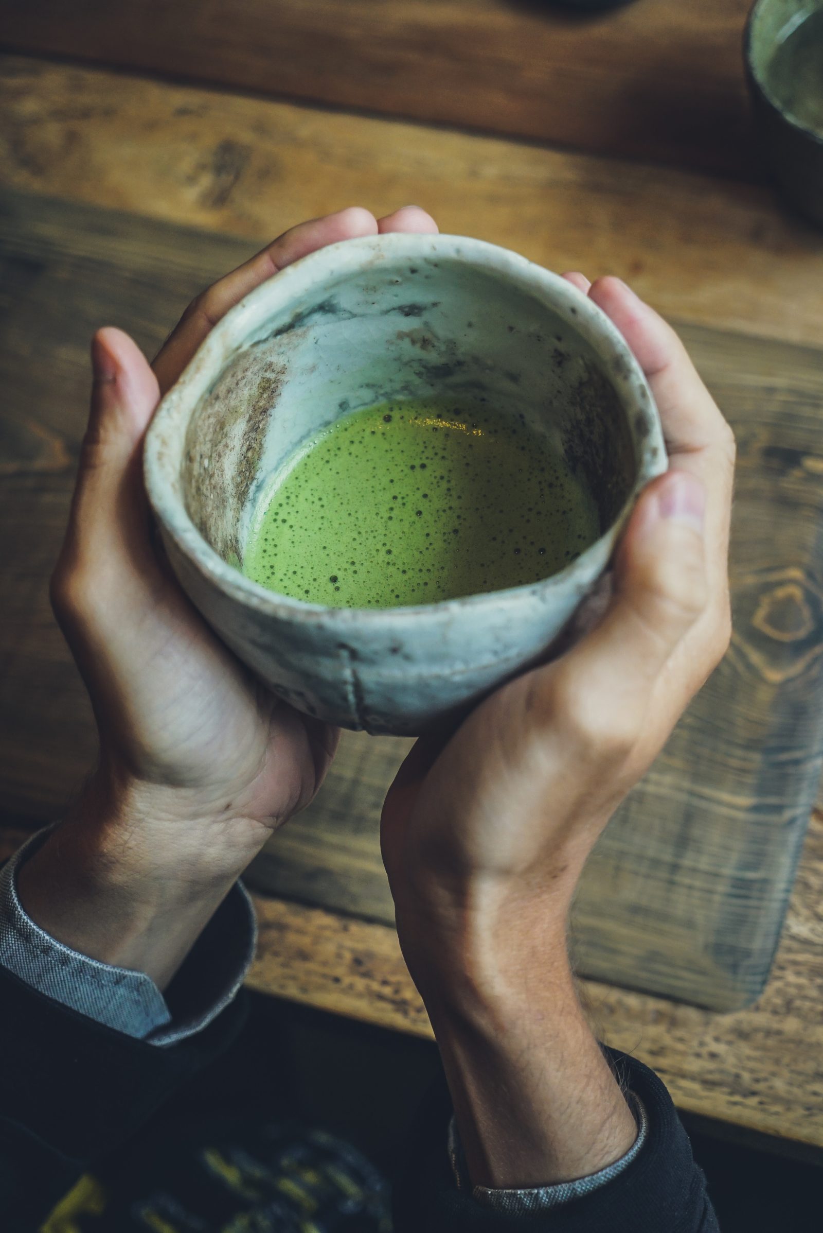 Matcha green tea in a clay cup in a person's hands
