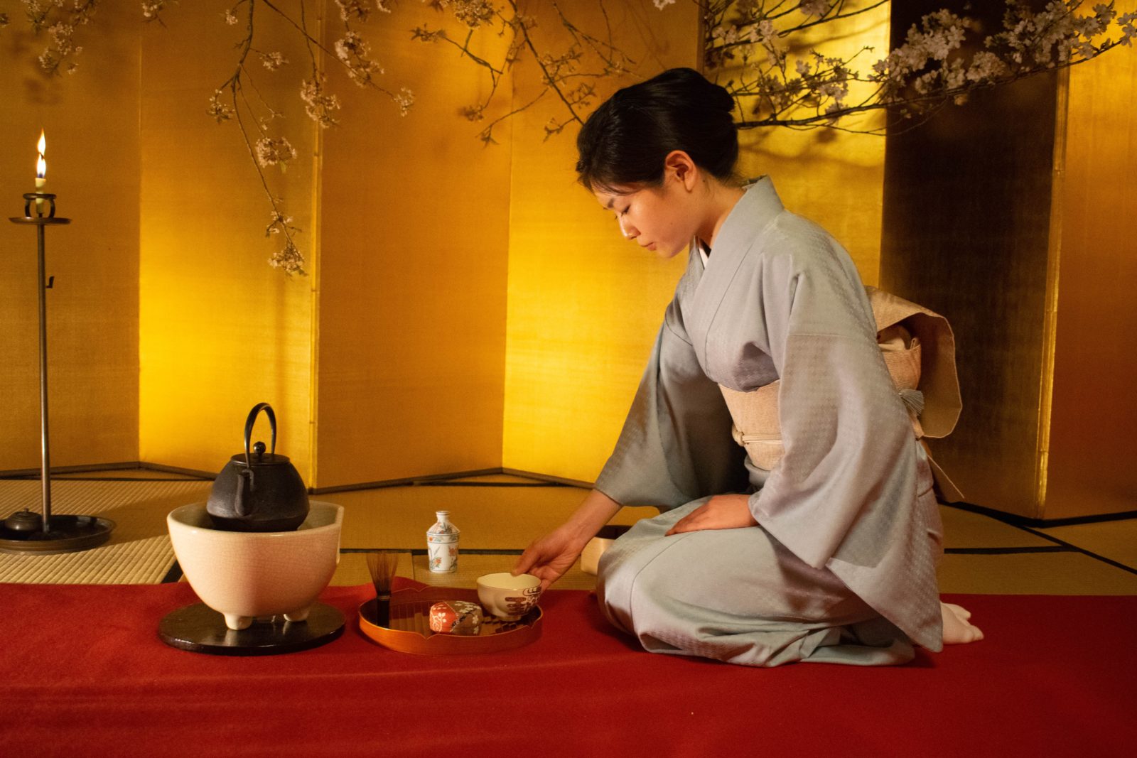 A woman seated and conducting a traditional Japanese tea ceremony