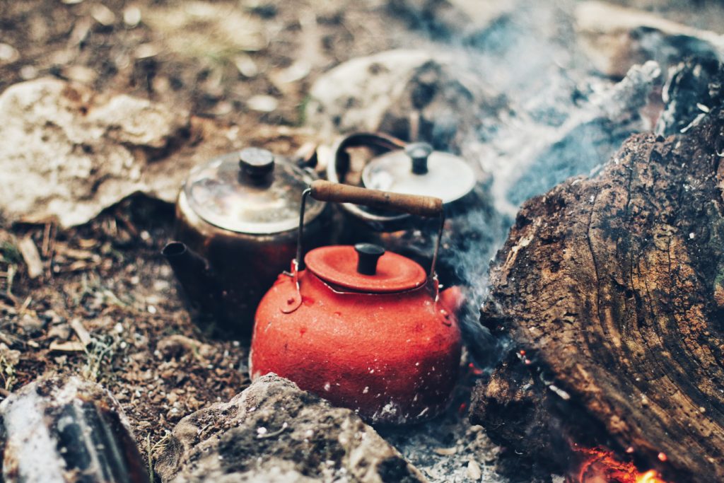 Three tea pots resting on hot charcoal outside