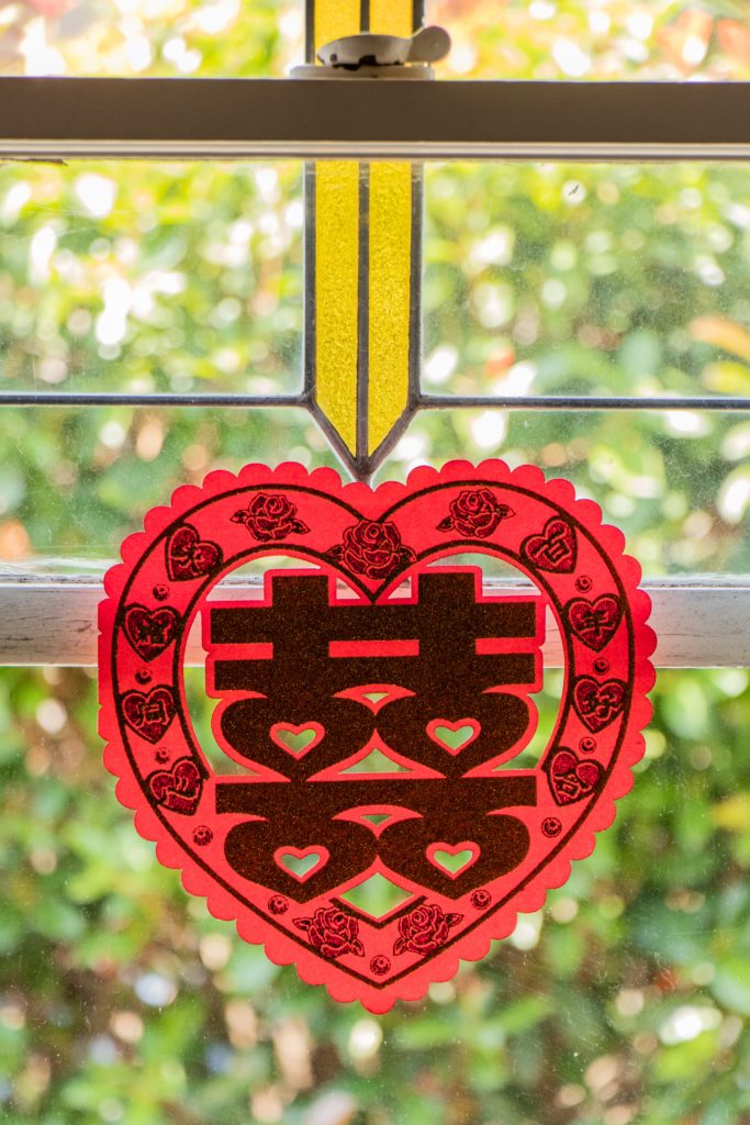 A heart hanging in a window with Chinese letters to symbolize tea and heart-health